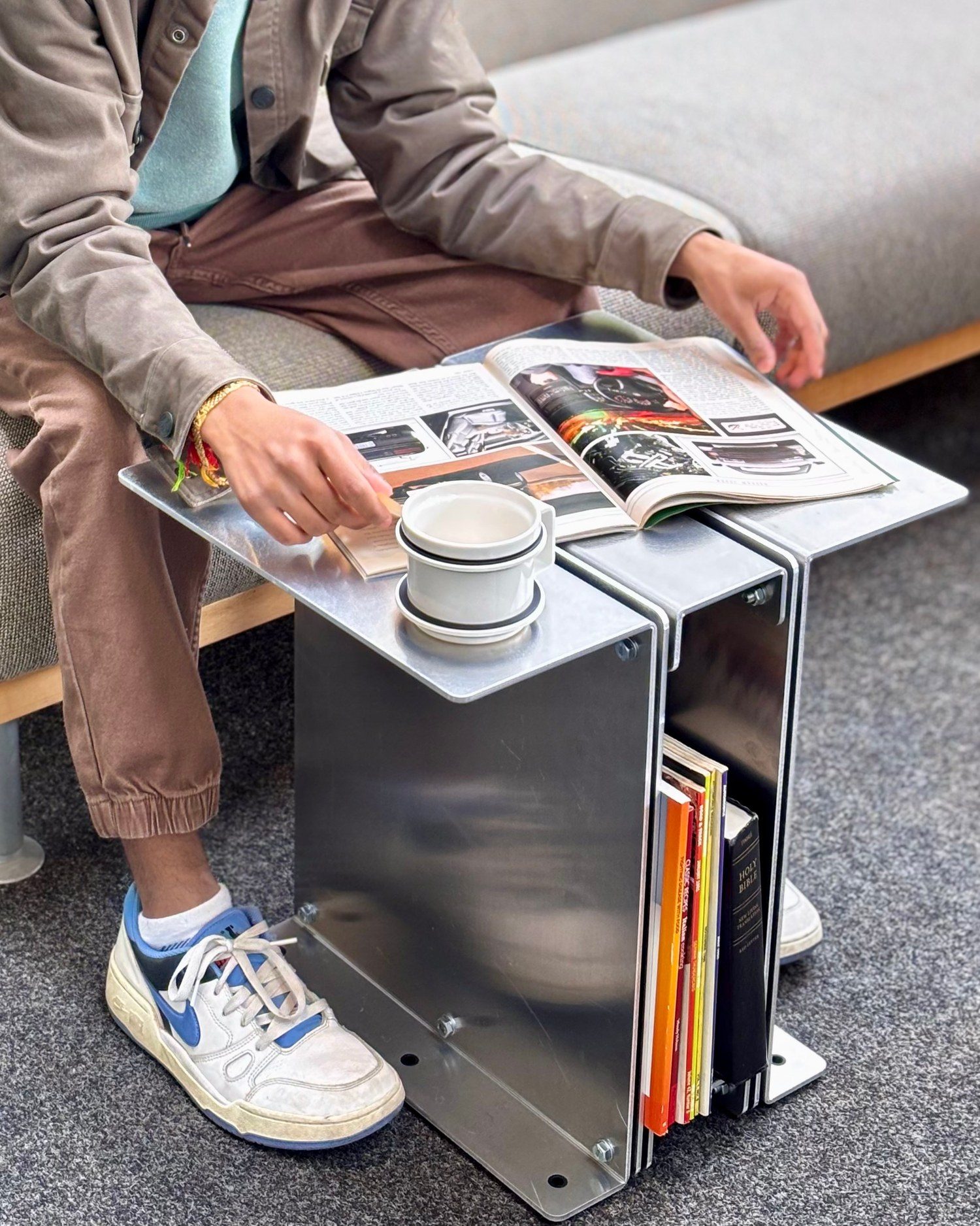 Someone reading a magazine spread open on the 3082 Book Table